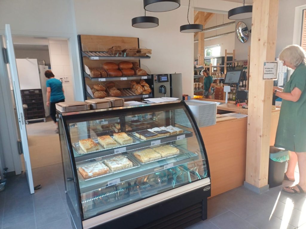 Eine Kühltheke ist mit Blechkuchen bestückt und im Hintergrund sieht man ein Brotregal